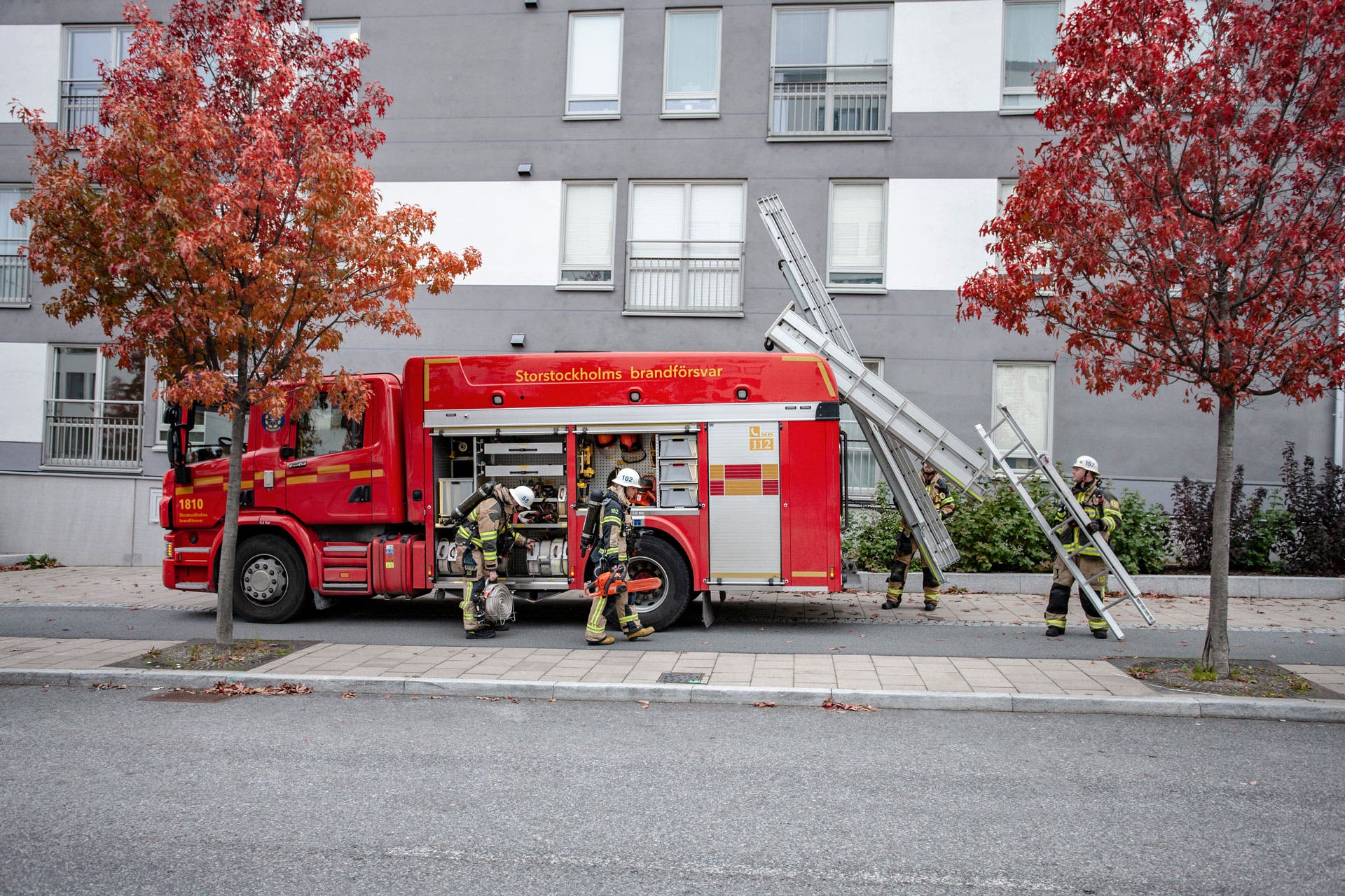 Brandmän framför en brandbil vid ett lägenhetshus