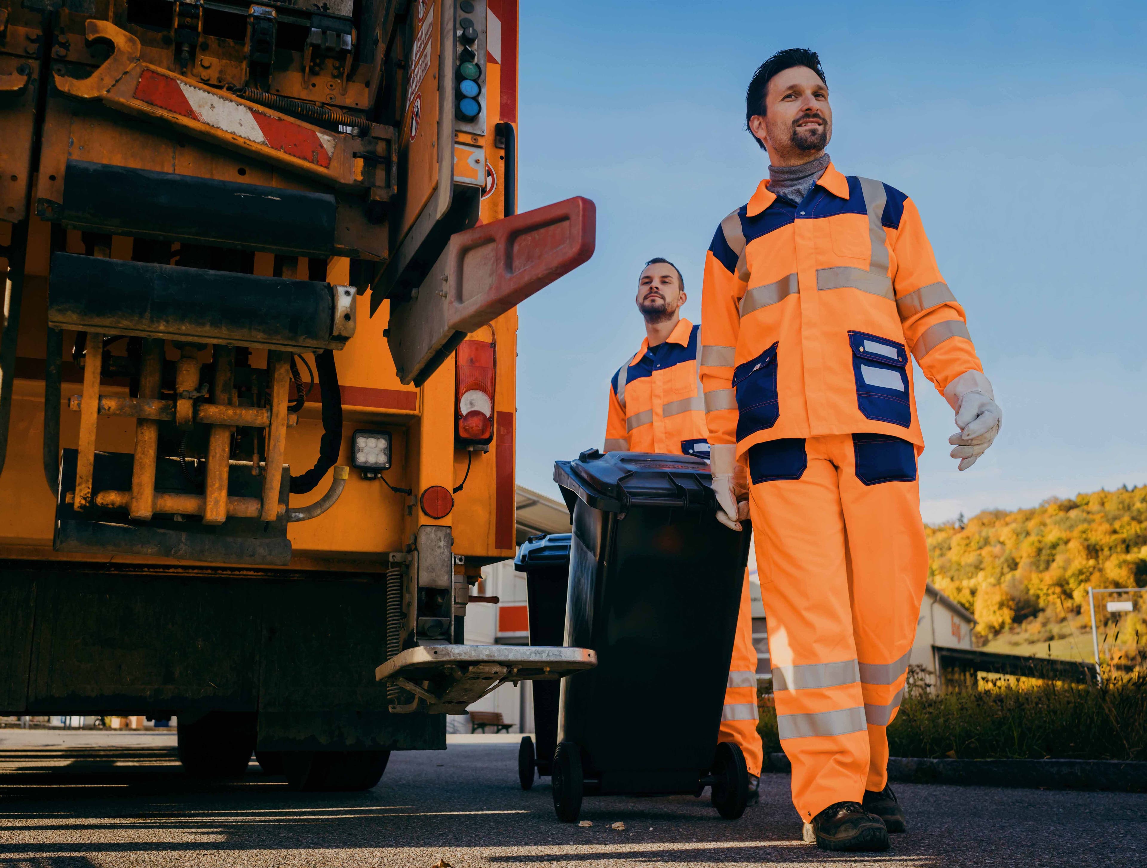 Renhållningsarbetare bredvid en sopbil